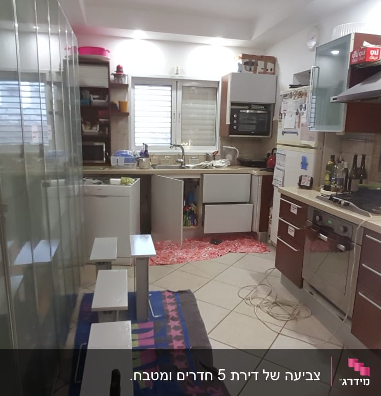 מטבח עם ארונות פתוחים וציוד צביעה על הרצפה